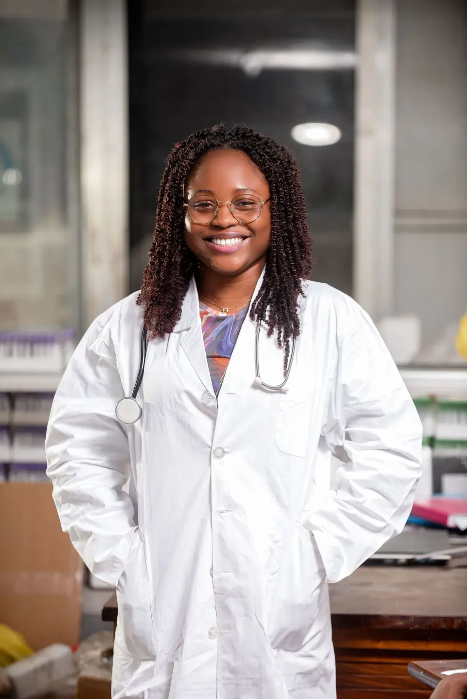 Smiling doctor in a white lab coat with a stethoscope, standing in a hospital room