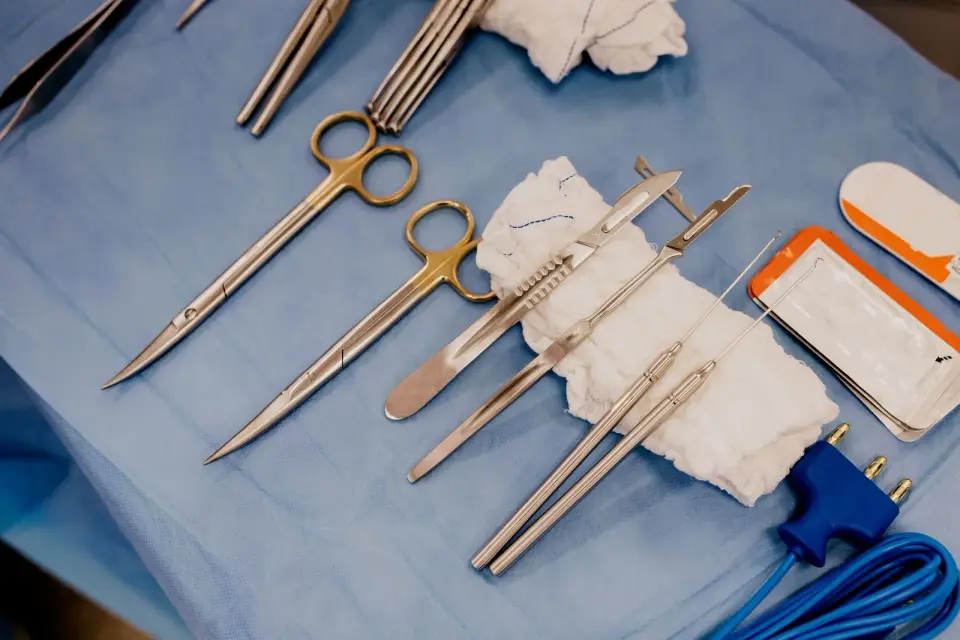 Scissors, forceps and other surgical instruments laid out on a blue sterile drape