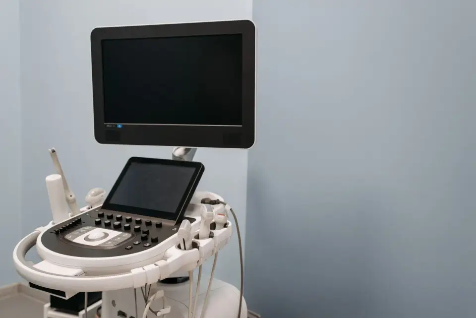 Ultrasound cart with a monitor, touchscreen and control panel in a clinic room