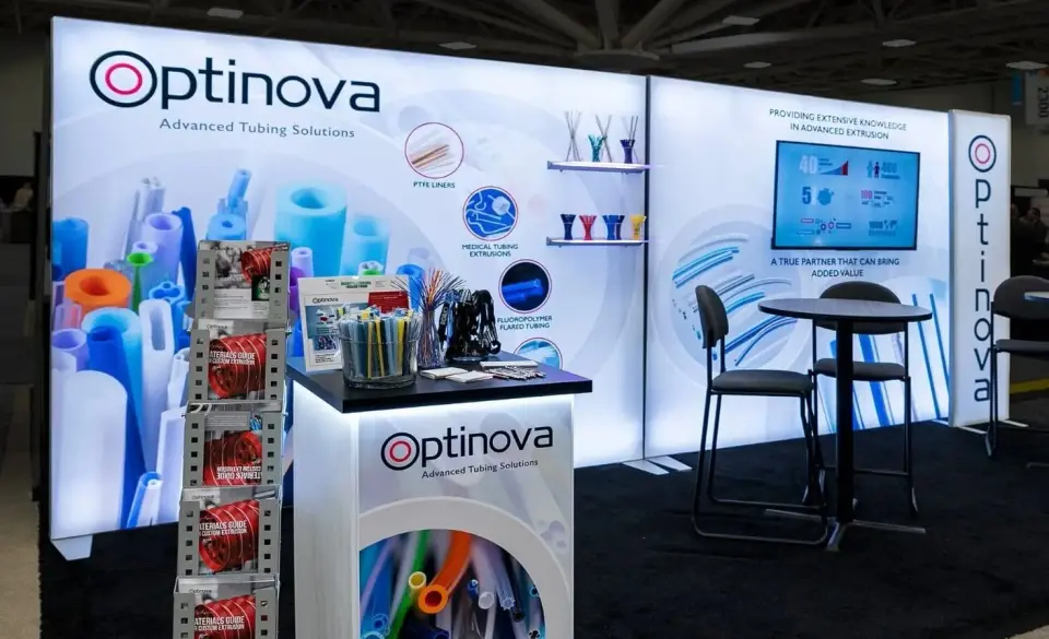 Optinova medical tubing trade show booth by Purple Exhibits with backlit walls, a sample counter and a high table