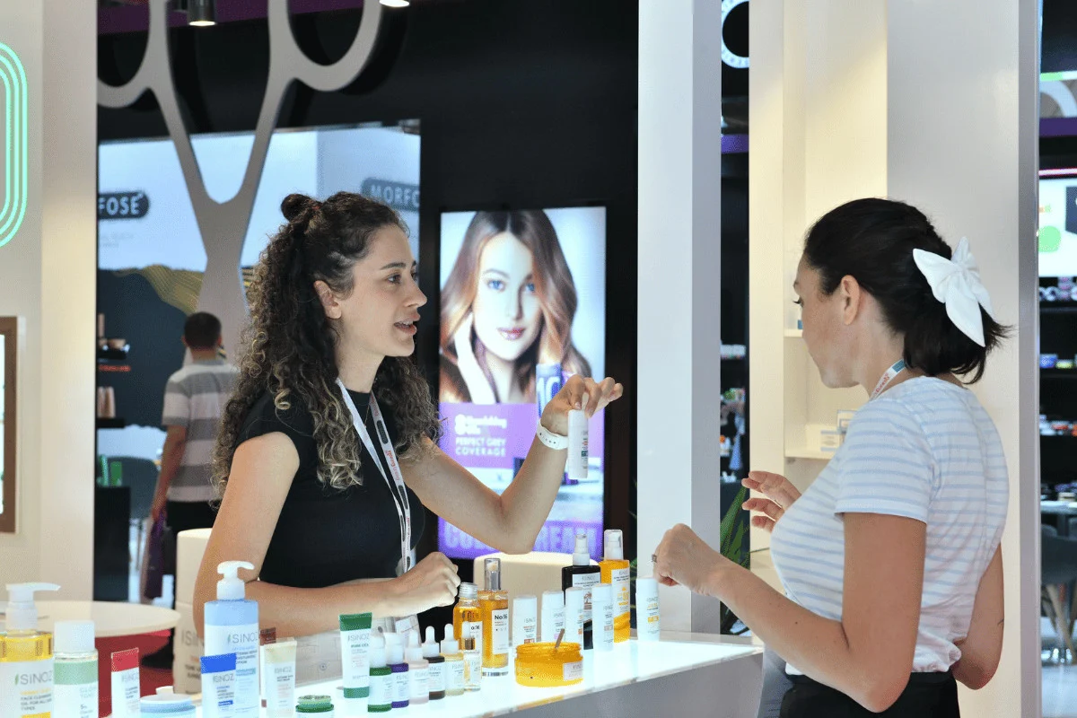 A skincare product demonstration at BeautyEurasia A woman exhibitor shows a skincare product to a visitor at a BeautyEurasia booth.