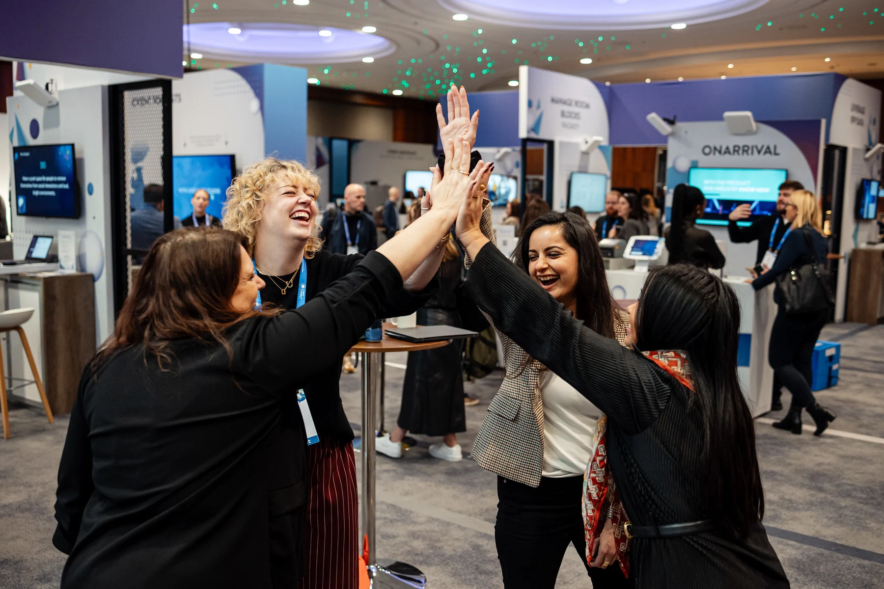 A team high-five at Cvent CONNECT Europe Women smile and high-five around a table at Cvent CONNECT Europe.