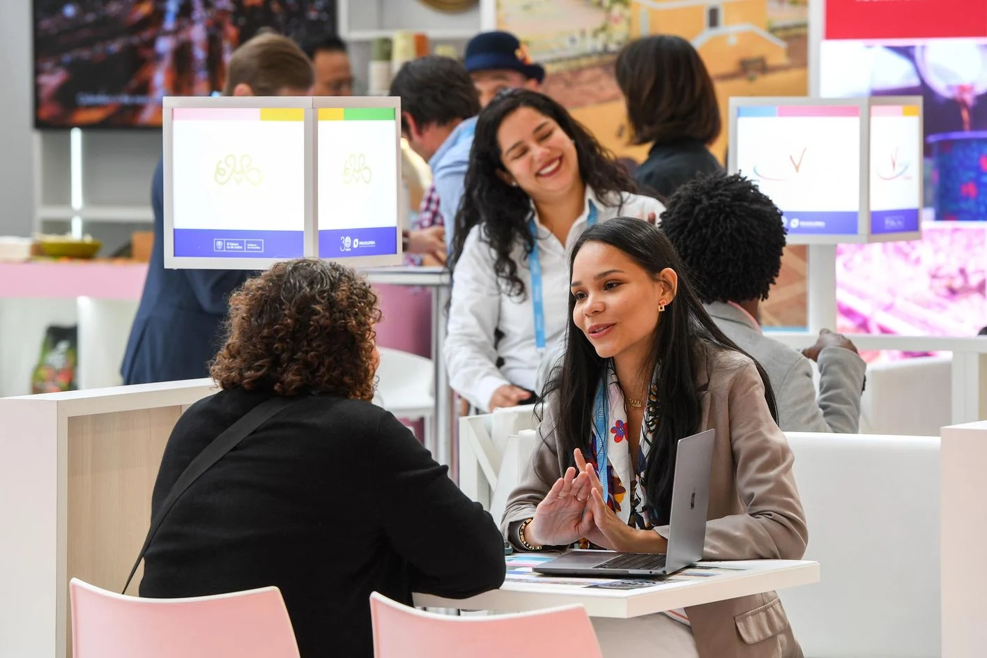 An exhibitor meeting at IMEX America A woman speaks with an attendee across a meeting table on the IMEX America exhibition floor.