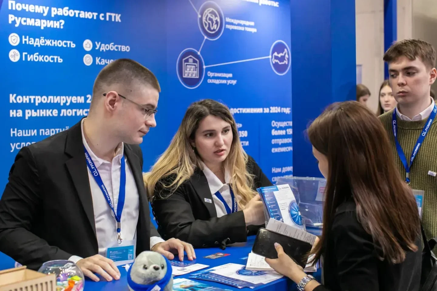 A face-to-face conversation at an exhibition booth Exhibitors and visitors talk face to face at a blue trade show booth.