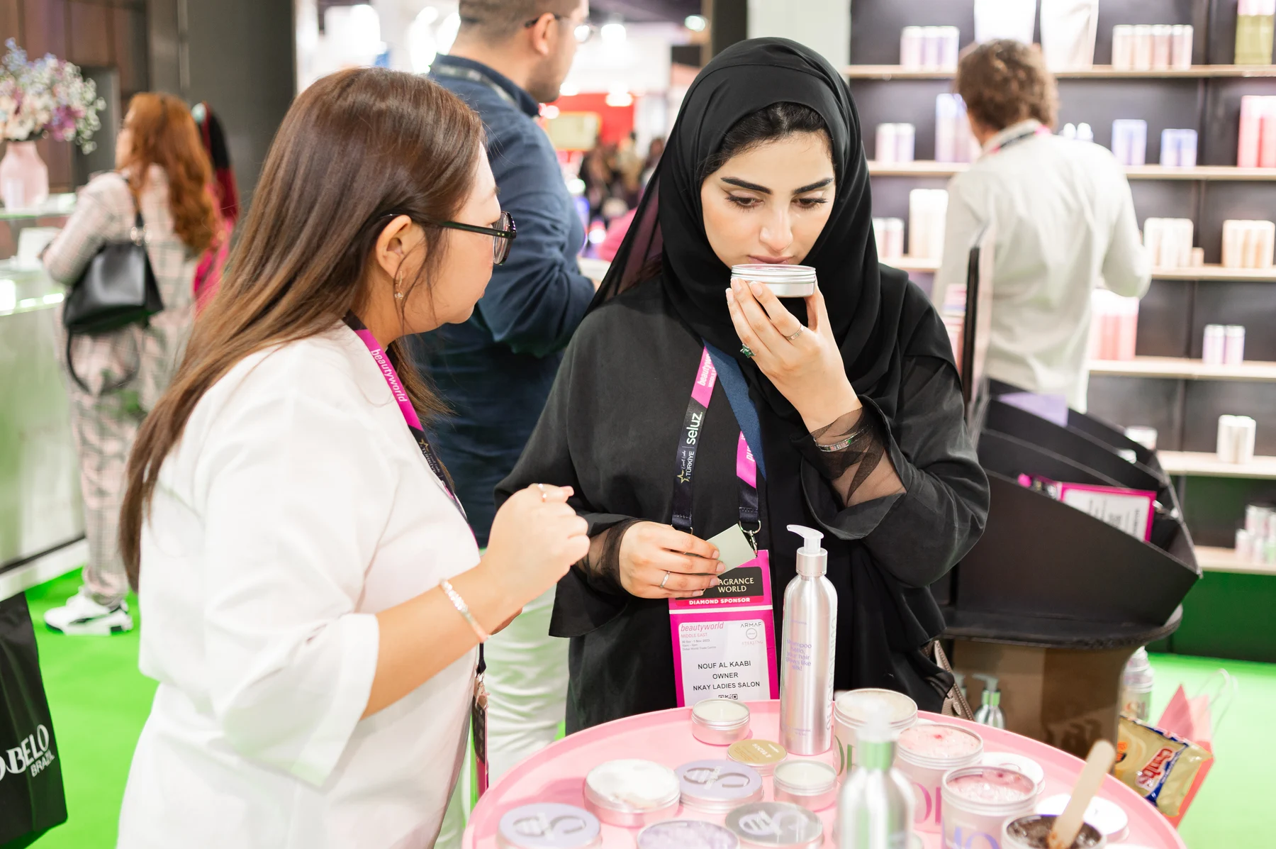A woman samples a cosmetic product while an exhibitor explains it at Beautyworld Middle East.