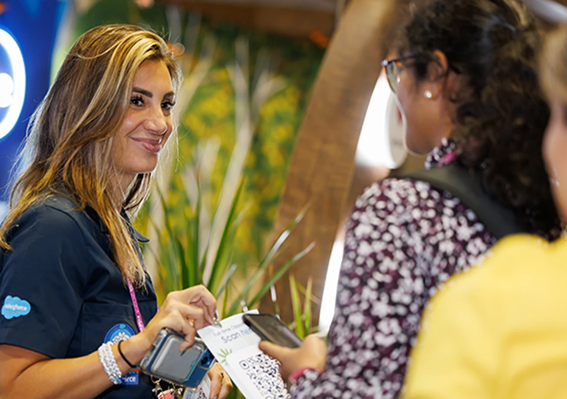 Capturing a contact at the Grace Hopper Celebration expo A Salesforce exhibitor and an attendee use a phone and QR code during a conversation at the Grace Hopper Celebration expo.