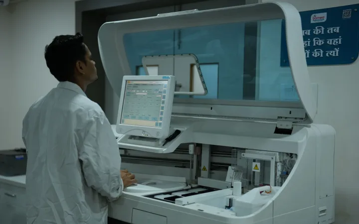 A laboratory technician operates a clinical analyzer.