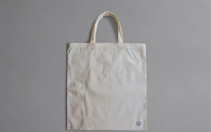 A plain canvas tote bag displayed against a neutral background.