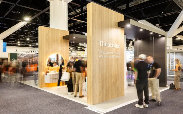 Timberline exhibit with tall timber panels, a black overhead frame, illuminated bathroom vanities and visitors in the aisle.