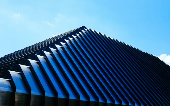 A contemporary building with a blue metal roof beneath a clear sky.