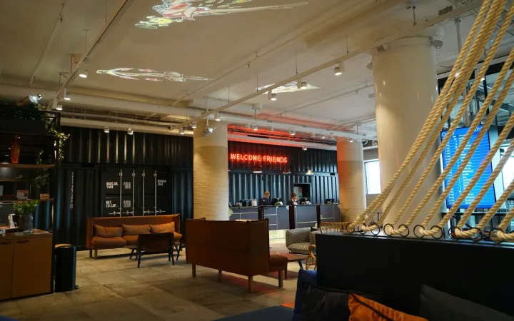 Hotel lobby with a reception desk, lounge seating, an information screen and projected ceiling graphics.