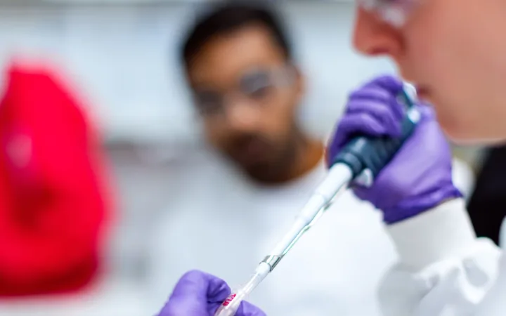 A woman scientist uses a pipette at a laboratory workstation.