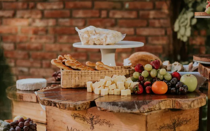 Cheese cubes, bread and fresh fruit arranged on rustic wood risers and a wine crate.