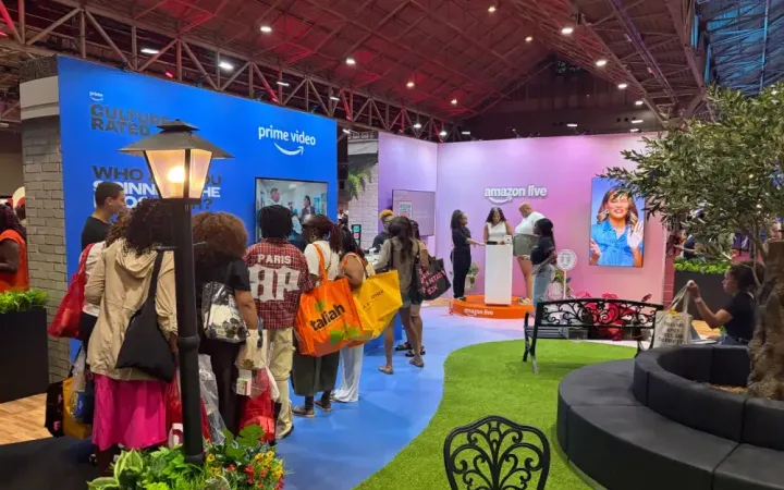 Visitors following a blue path through Amazon’s activation with Prime Video and Amazon Live walls, artificial turf, trees and curved seating.