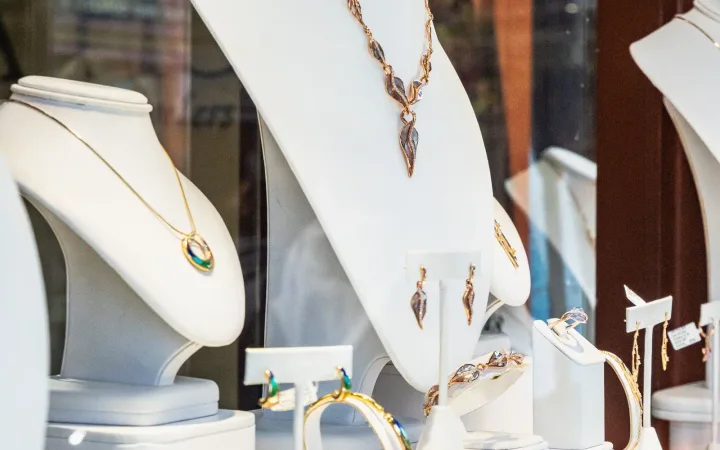 Jewelry displayed on necklace busts inside an illuminated boutique window.