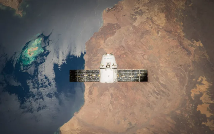 A spacecraft above Earth with ocean and land visible below.