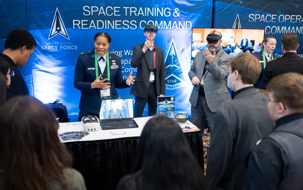 Capt. Kayla Edwards explains interactive training to visitors at the STARCOM booth at the 40th Space Symposium.