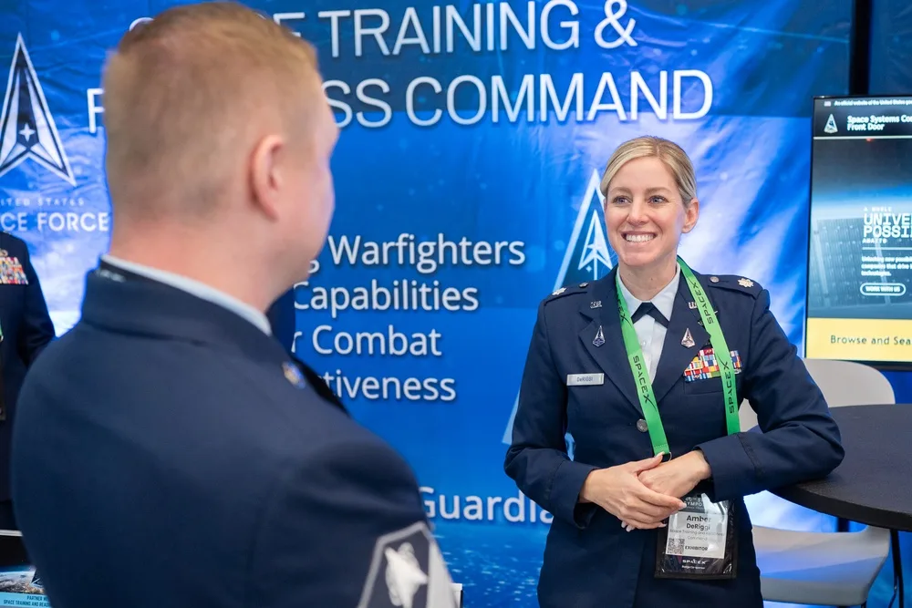 Lt. Col. Amber DeRiggi speaks with a visitor at the STARCOM booth during the 40th Space Symposium.