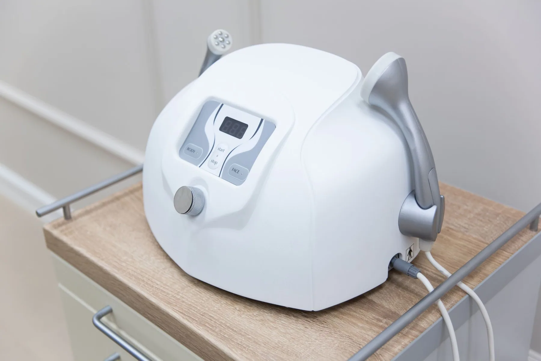 A facial device stands on a white cabinet.