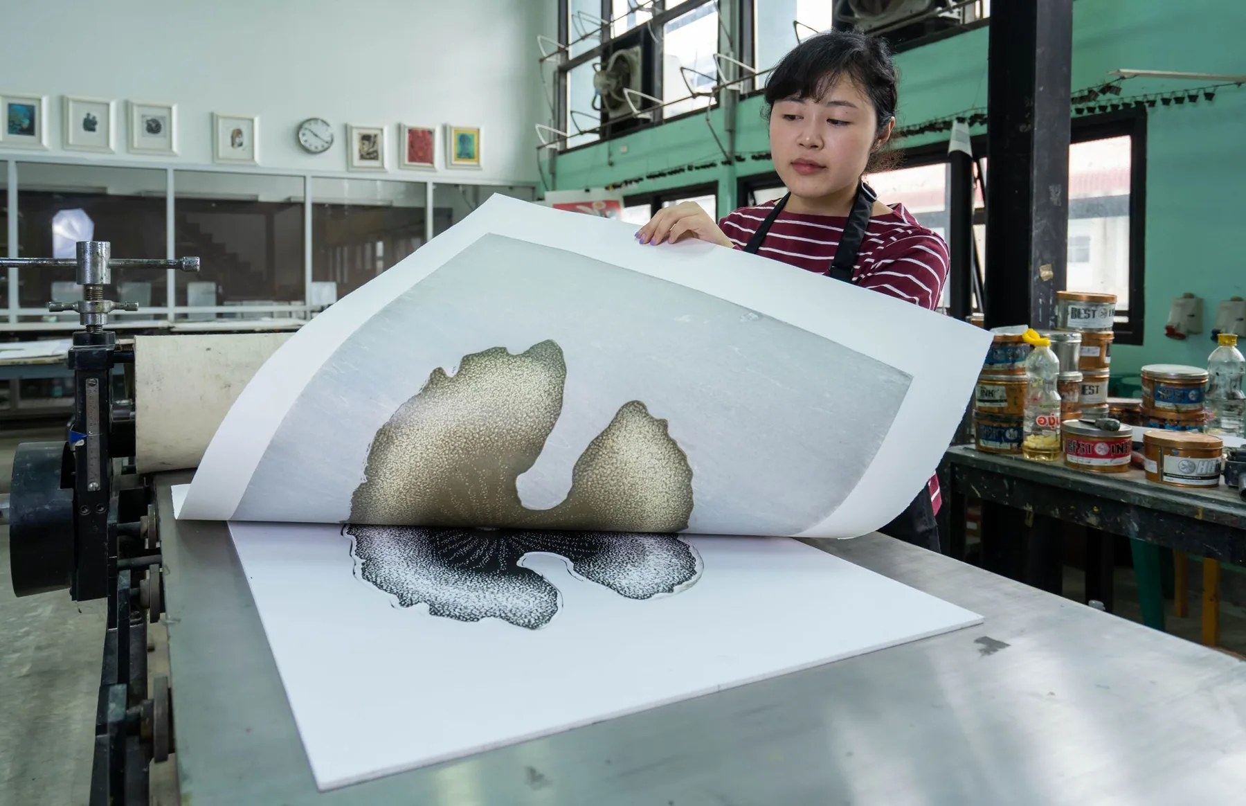 A woman inspects a freshly printed design in a printing studio.