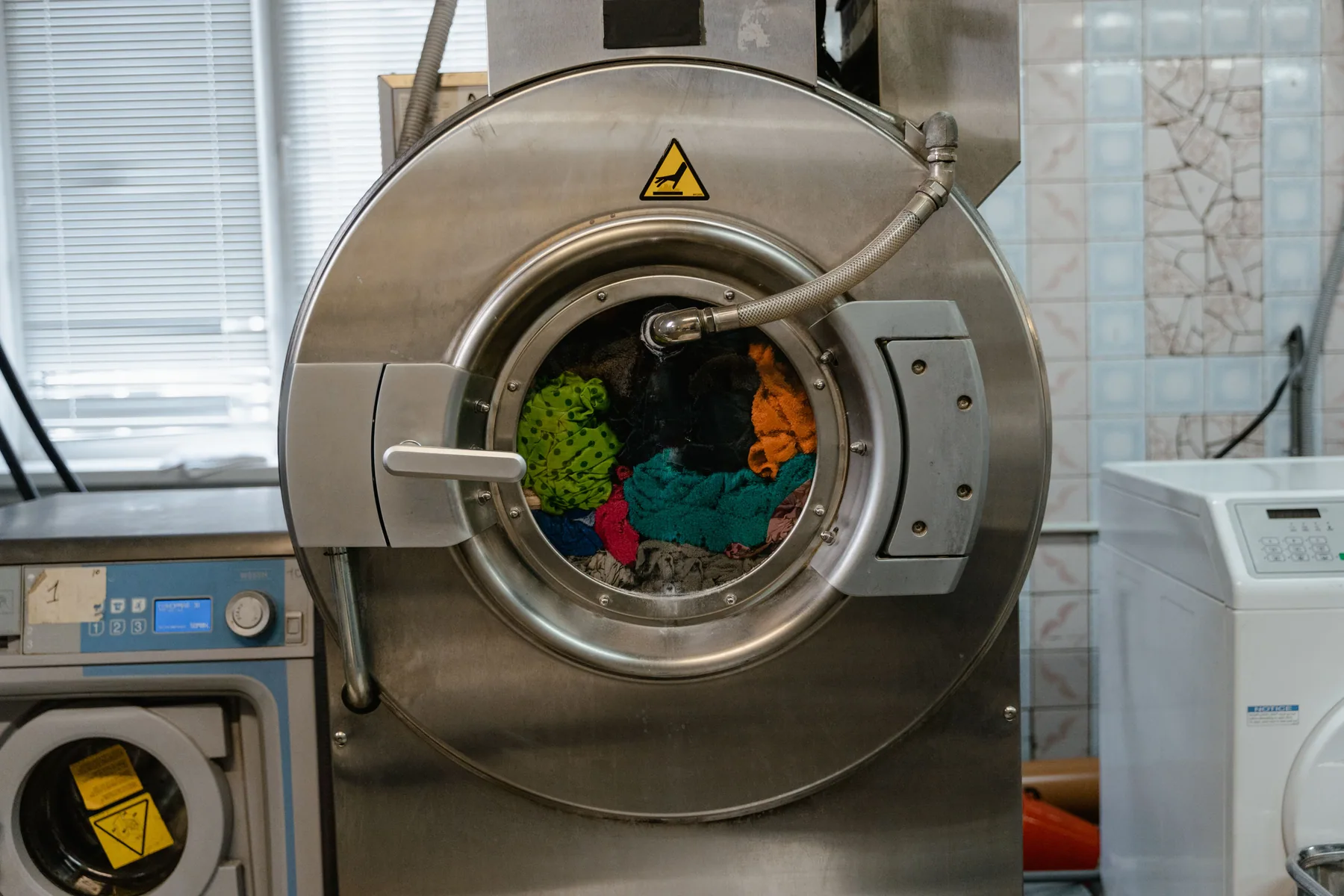 Close view of an industrial washing machine with textiles inside.