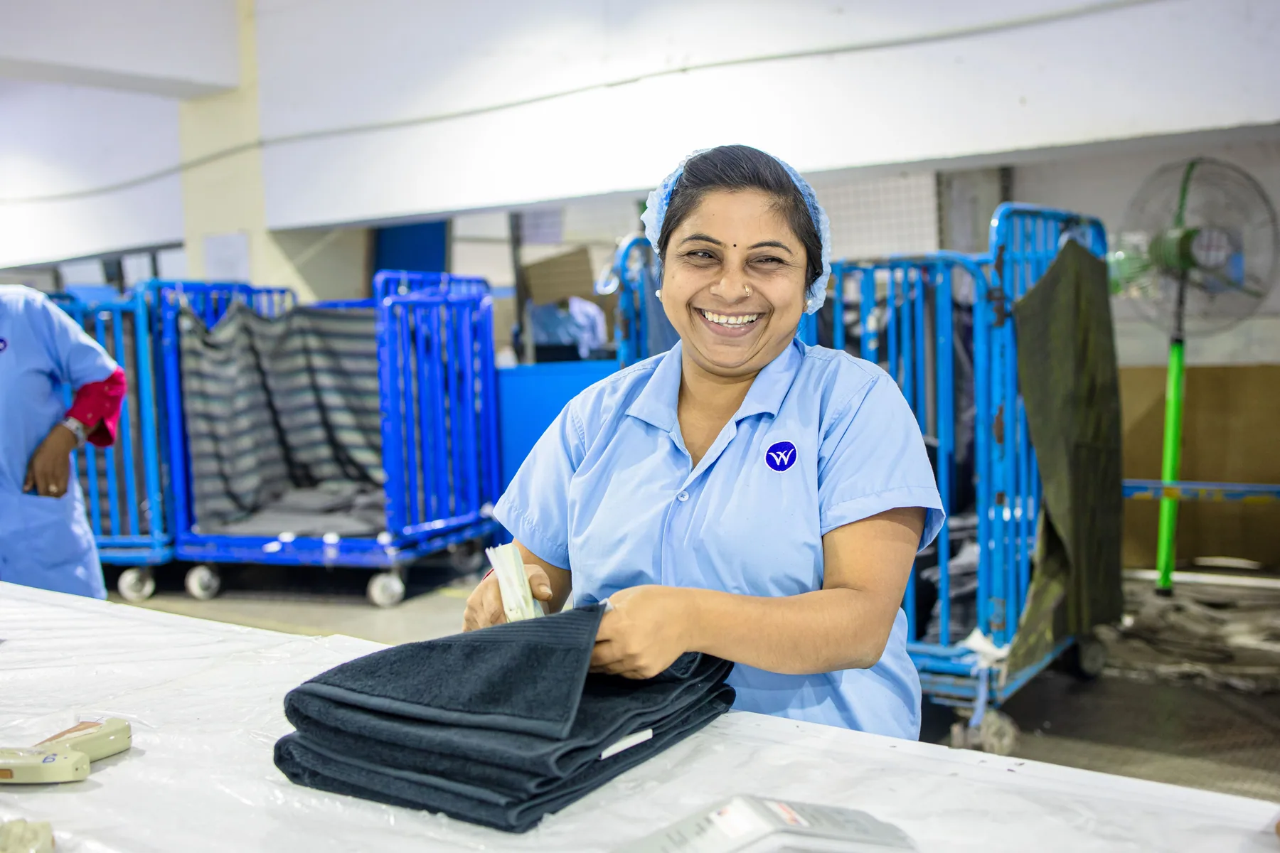 A textile worker folds garments in a factory.