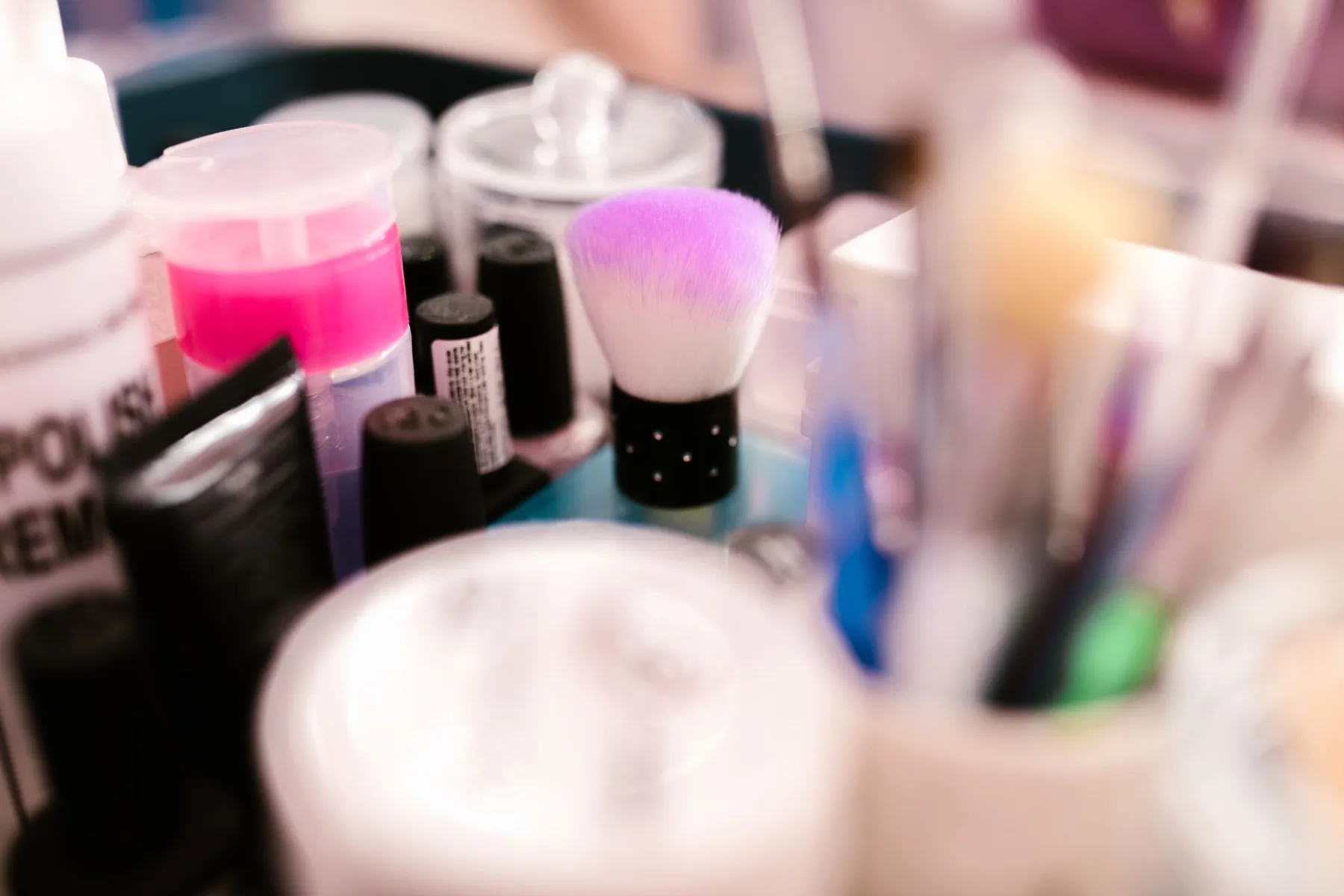 Makeup brushes and cosmetic containers on a vanity.