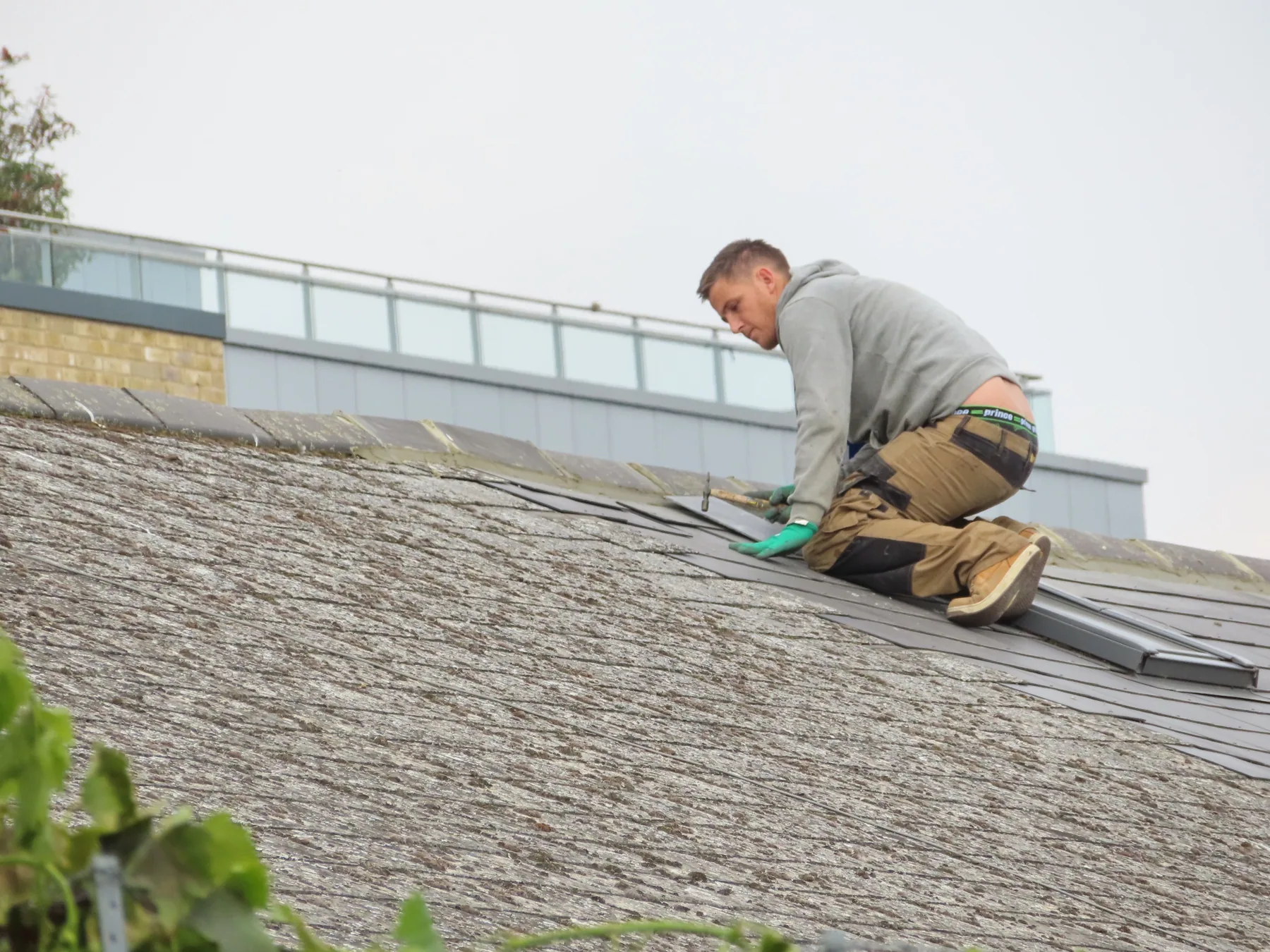 A worker installs roof shingles outdoors.