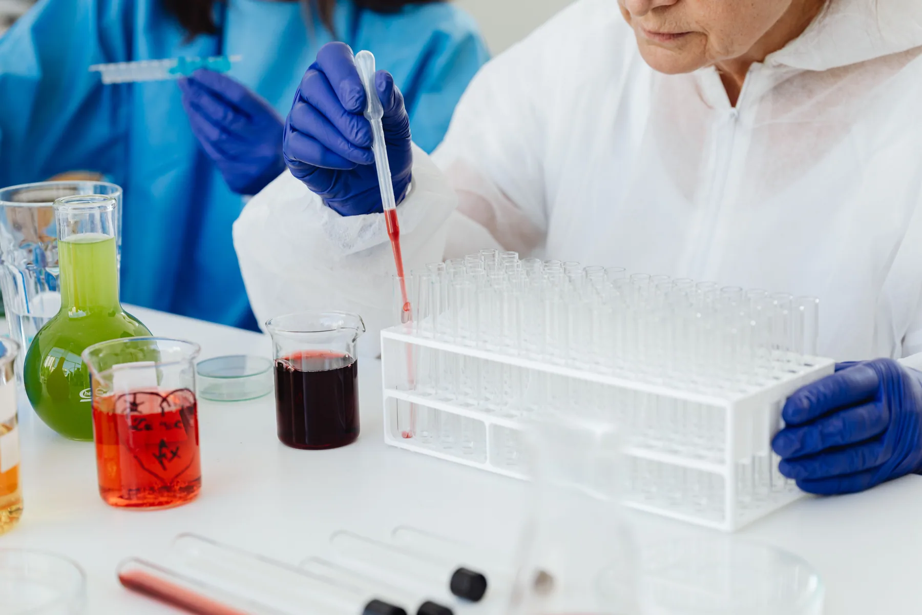A scientist uses a pipette with test tubes at a laboratory bench.