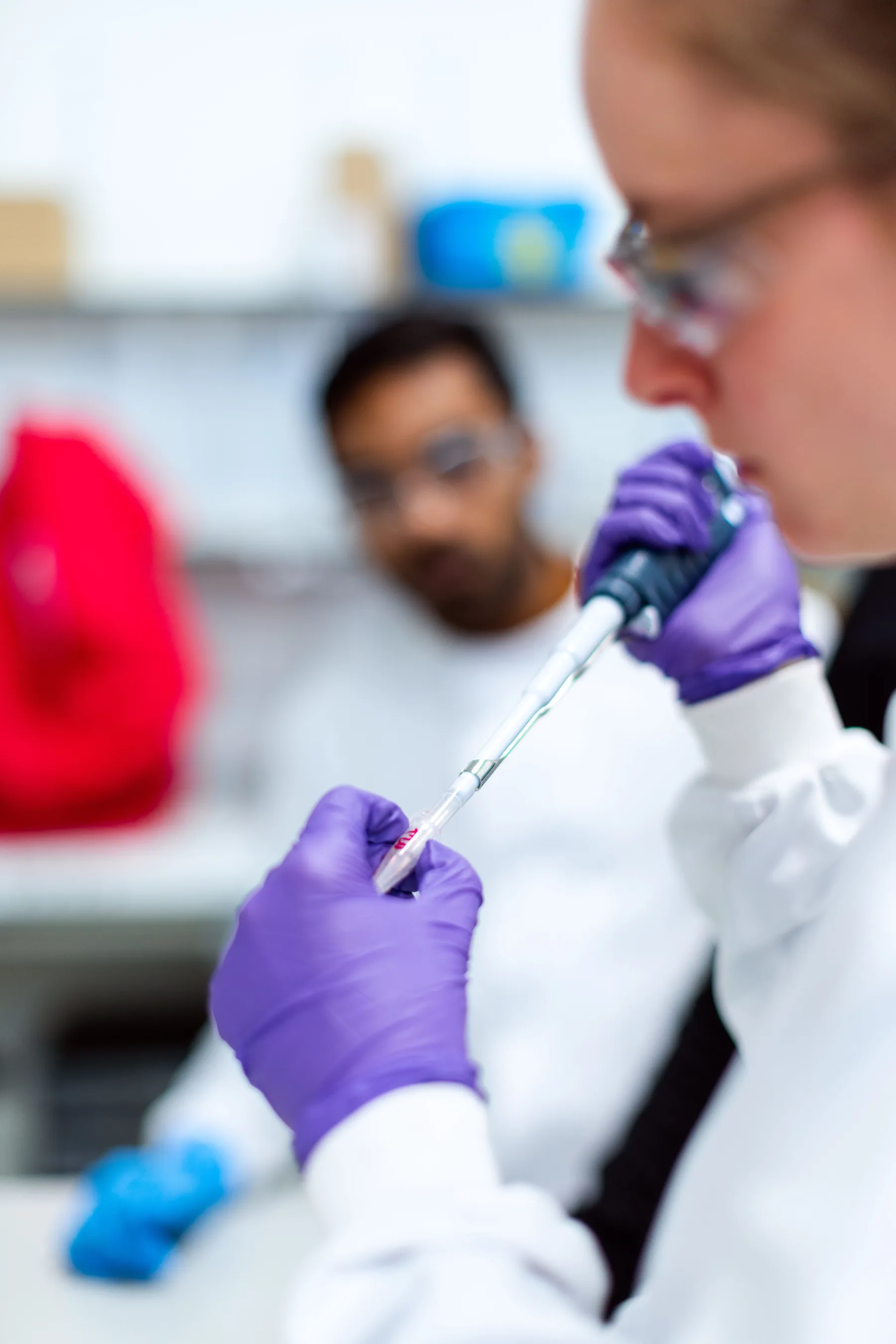A woman scientist uses a pipette at a laboratory workstation.