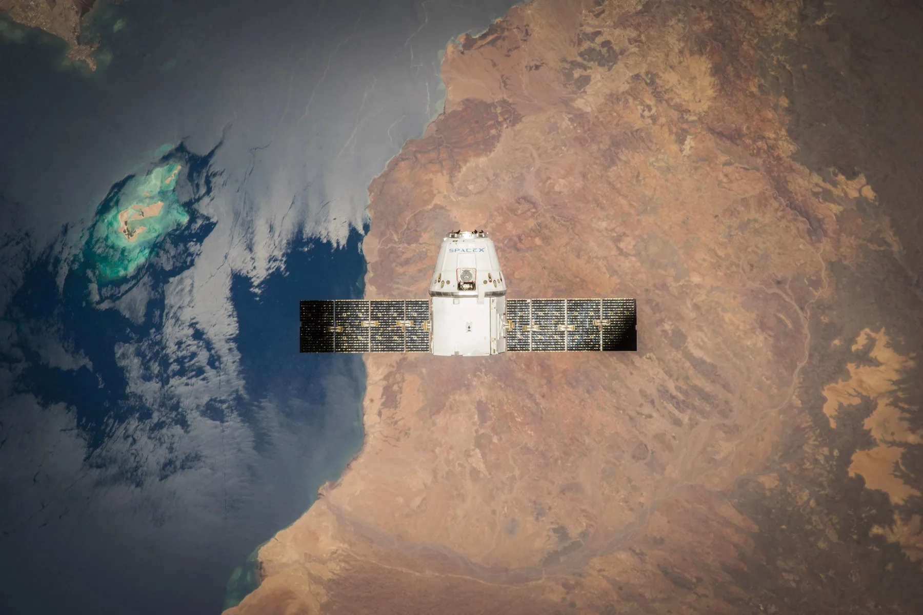A spacecraft above Earth with ocean and land visible below.