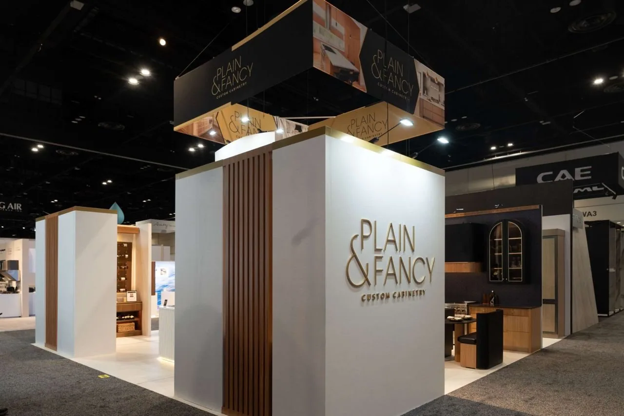 Plain & Fancy exhibit with a white brand wall, wood slats and cabinetry settings.
