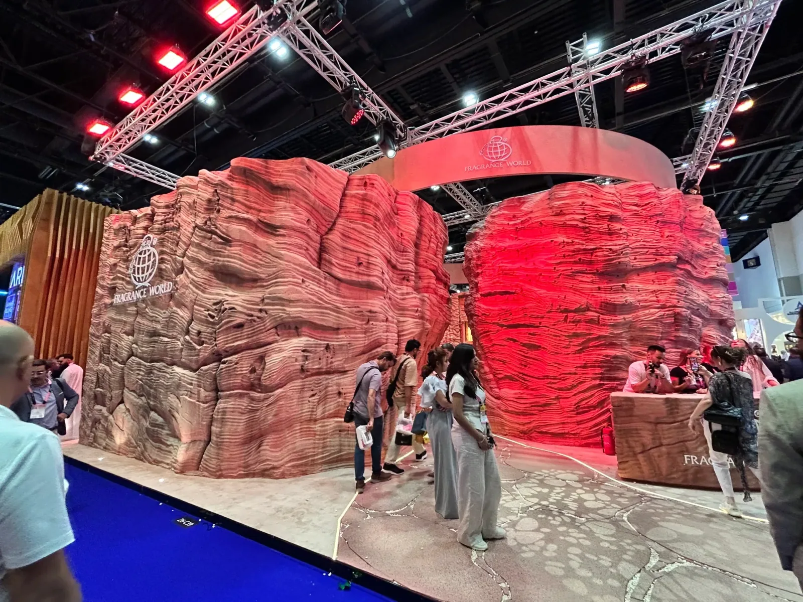 Visitors standing at the open frontage of the French Avenue fragrance exhibit, framed by red textured walls.