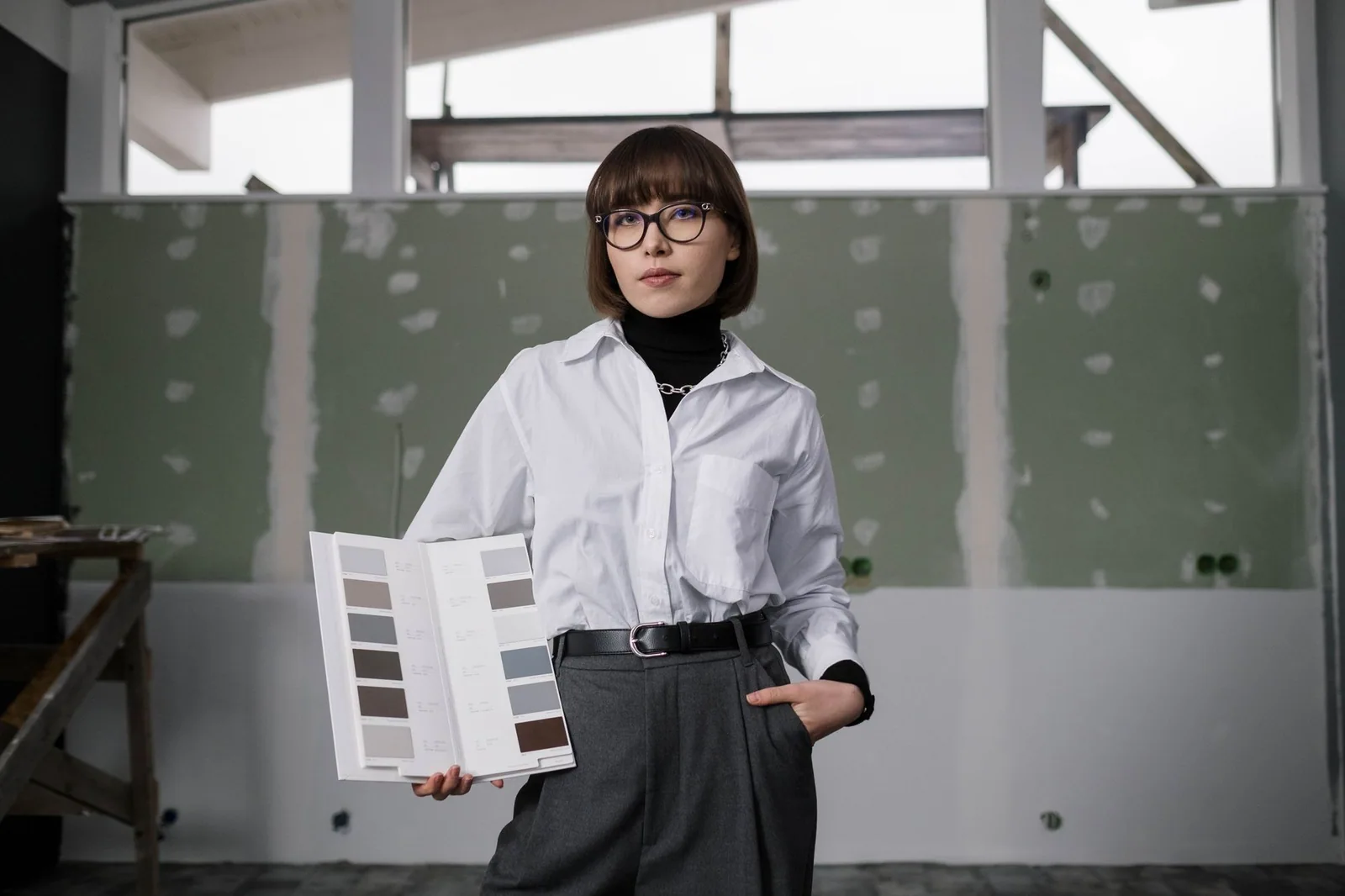 Adult woman in professional clothing holding a catalog of interior color samples.