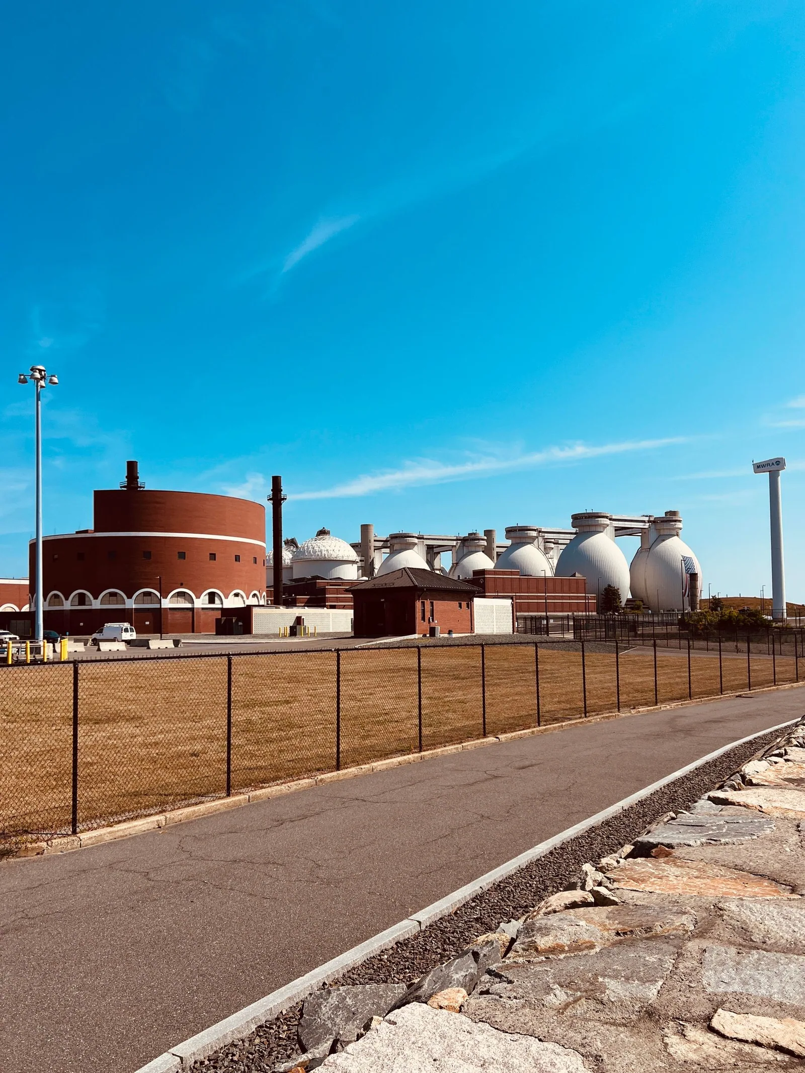 Domed industrial treatment tanks and red-brick buildings under a clear blue sky.