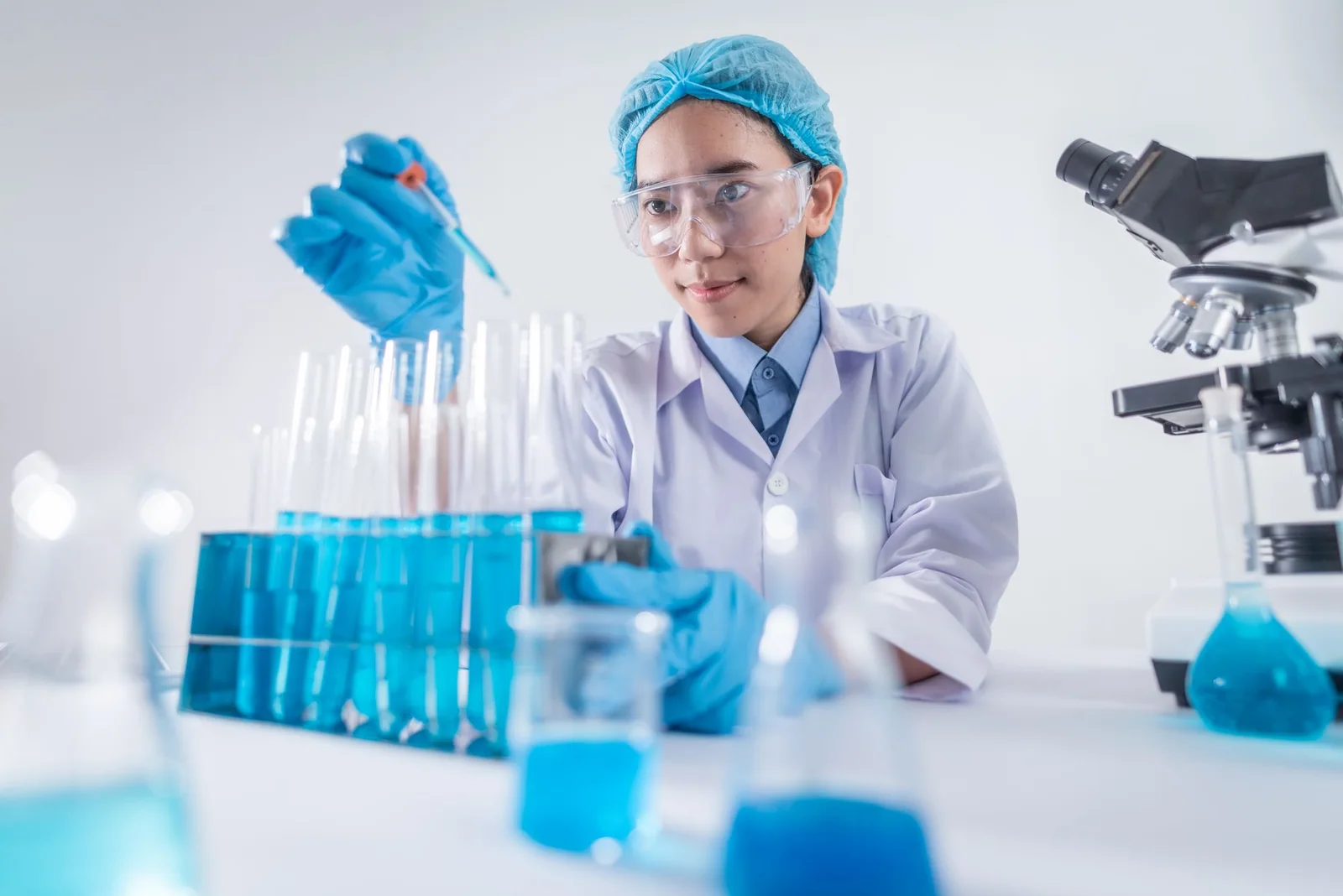 Woman scientist using laboratory equipment beside test tubes