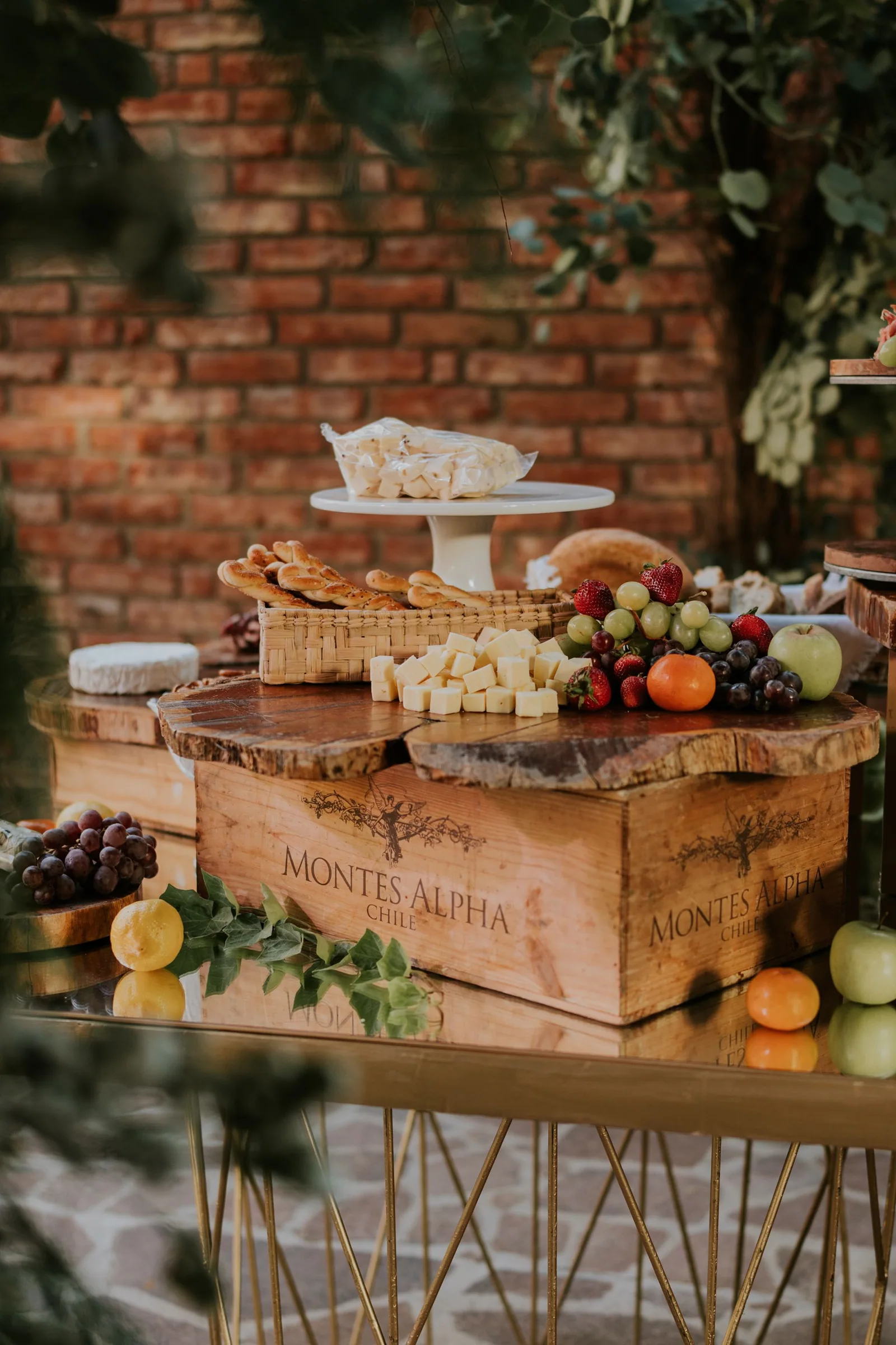 Cheese cubes, bread and fresh fruit arranged on rustic wood risers and a wine crate.