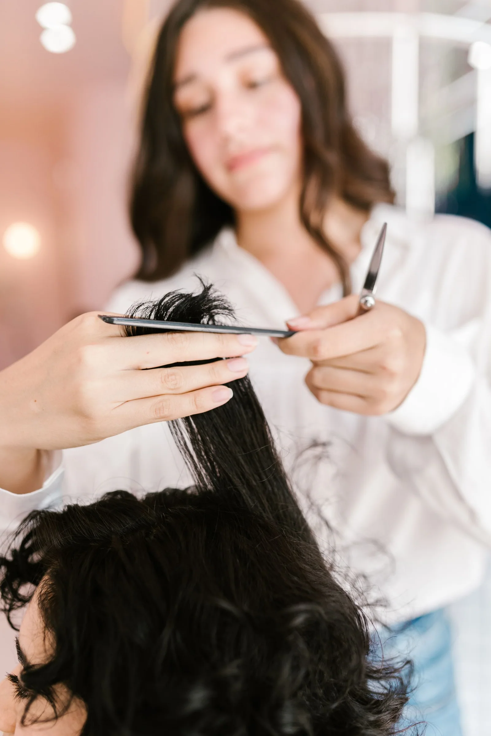 Professional hairstylist cutting a woman’s hair in a salon