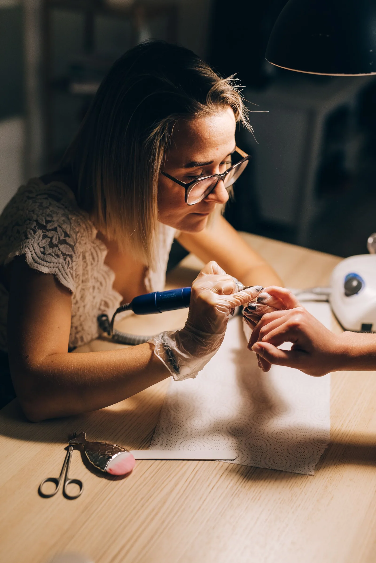 Woman nail technician using a manicure tool at her workstation