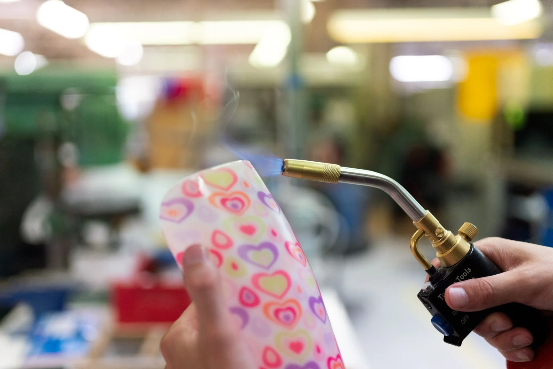 A technician heats and shapes a colorful ankle-foot orthosis in a workshop.
