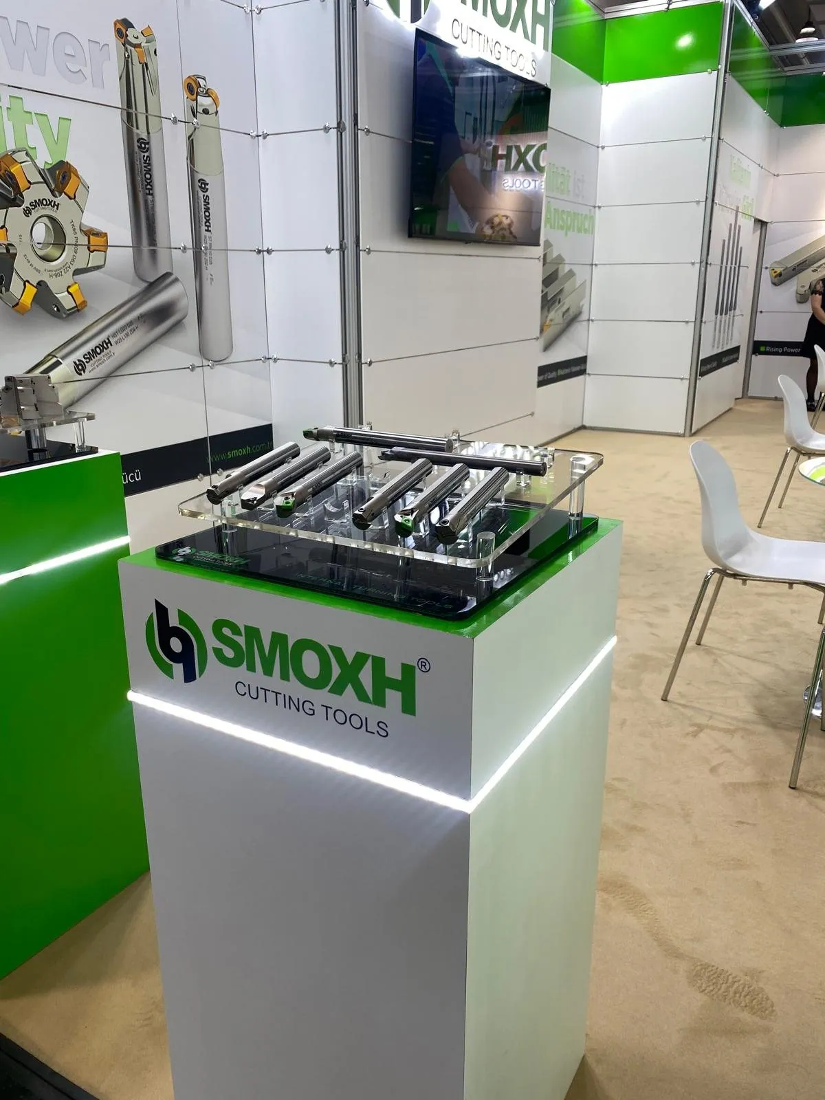 SMOXH cutting-tool exhibit detail with rows of metal tools on an illuminated green-and-white display plinth.