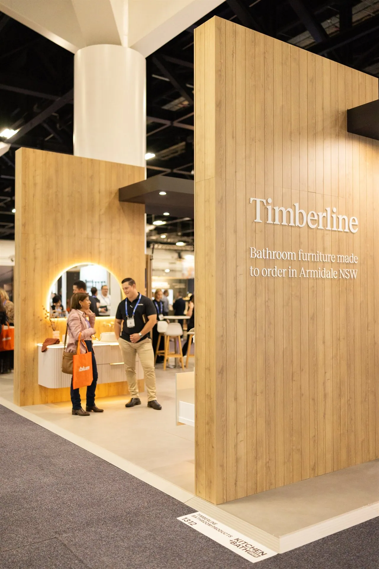 Close view of Timberline’s tall timber-clad exhibit frame beside a rounded illuminated mirror and bathroom vanity.