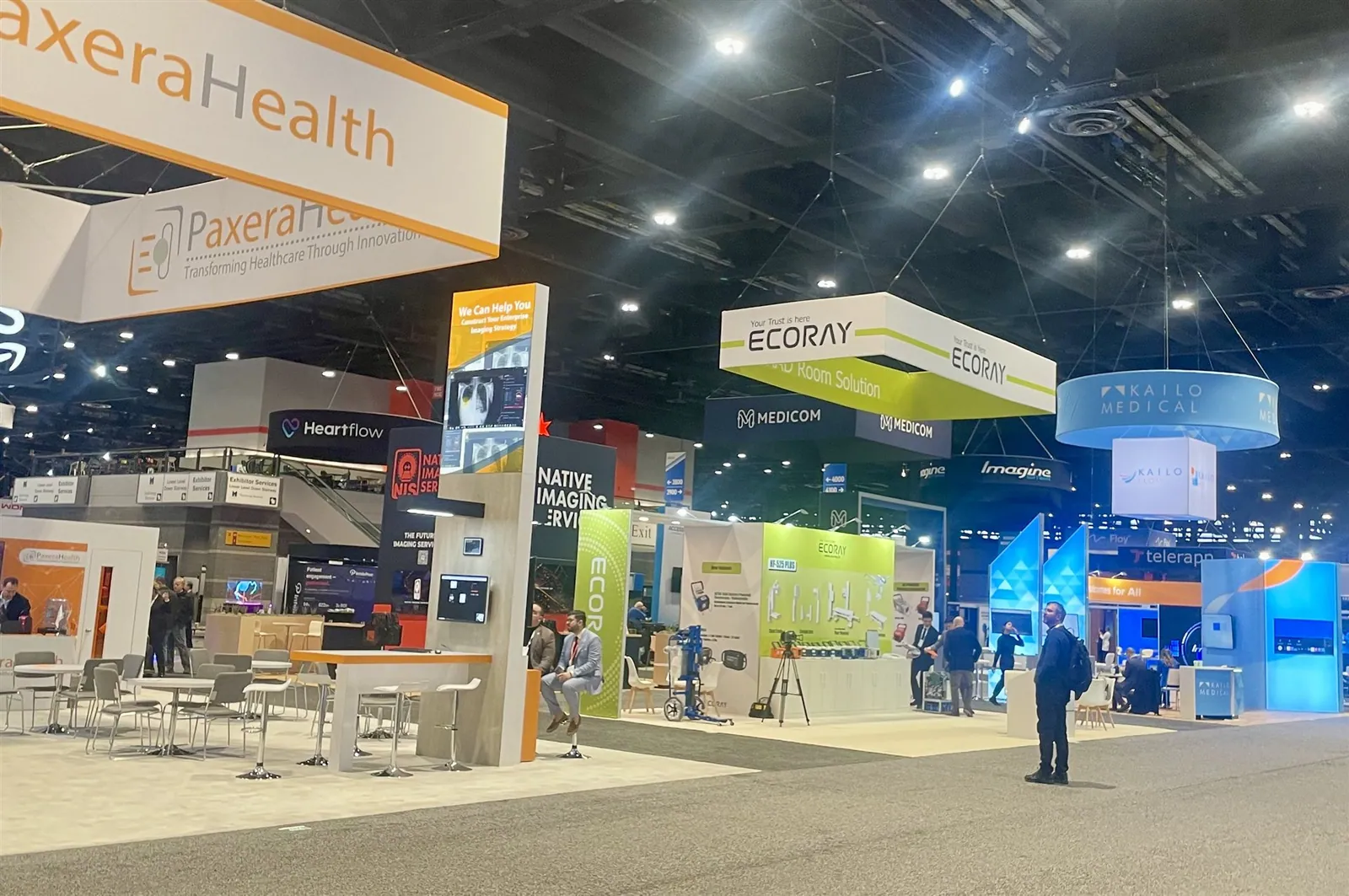 Medical-imaging show floor with Ecoray and PaxeraHealth overhead signs, clinical-technology displays and open visitor aisles.