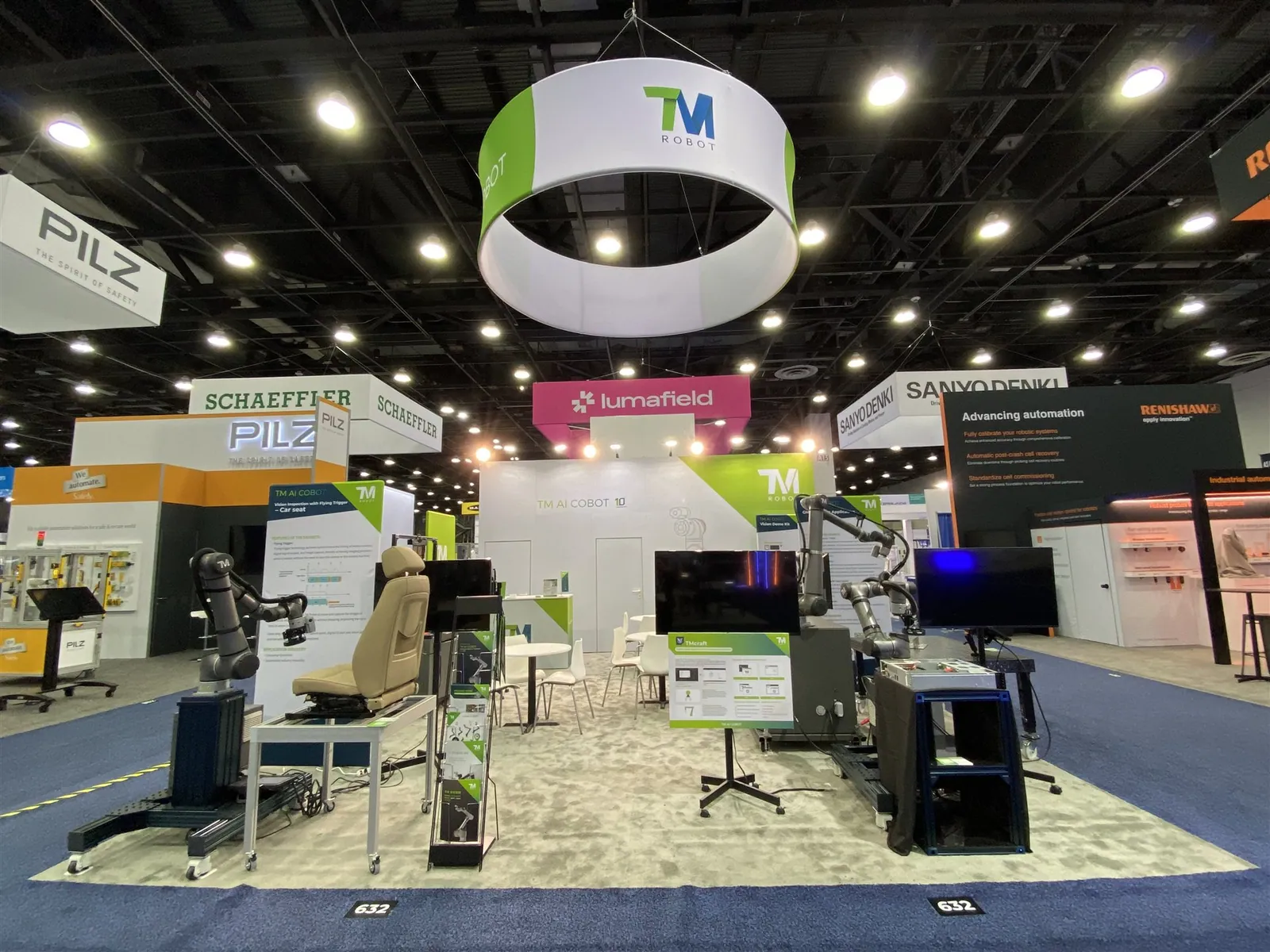 Techman Robot exhibit with robotic demonstration stations, equipment screens and a circular white-and-green overhead sign.