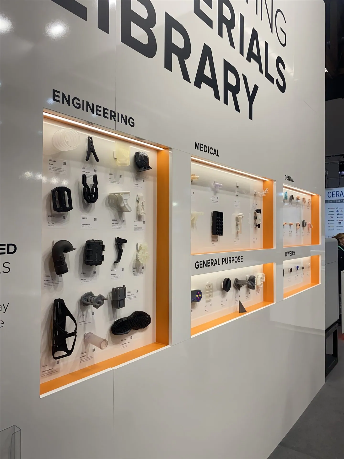 Illuminated sample niches organized under Engineering, Medical, Dental, General Purpose and Jewelry headings in a materials-library wall.