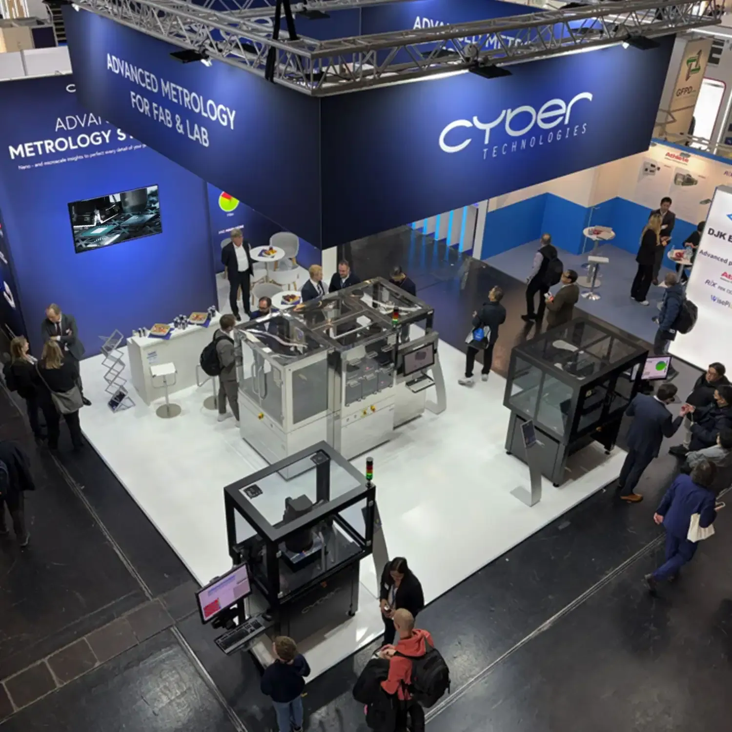 Overhead view of cyberTECHNOLOGIES’ exhibit with enclosed measurement systems, screens and visitors around the equipment.