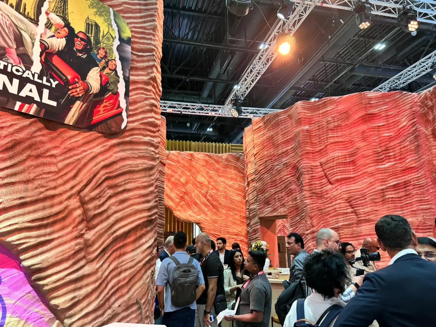 Visitors exploring French Avenue's fragrance exhibit between tall sculpted rock-textured walls, integrated graphics and dramatic lighting.