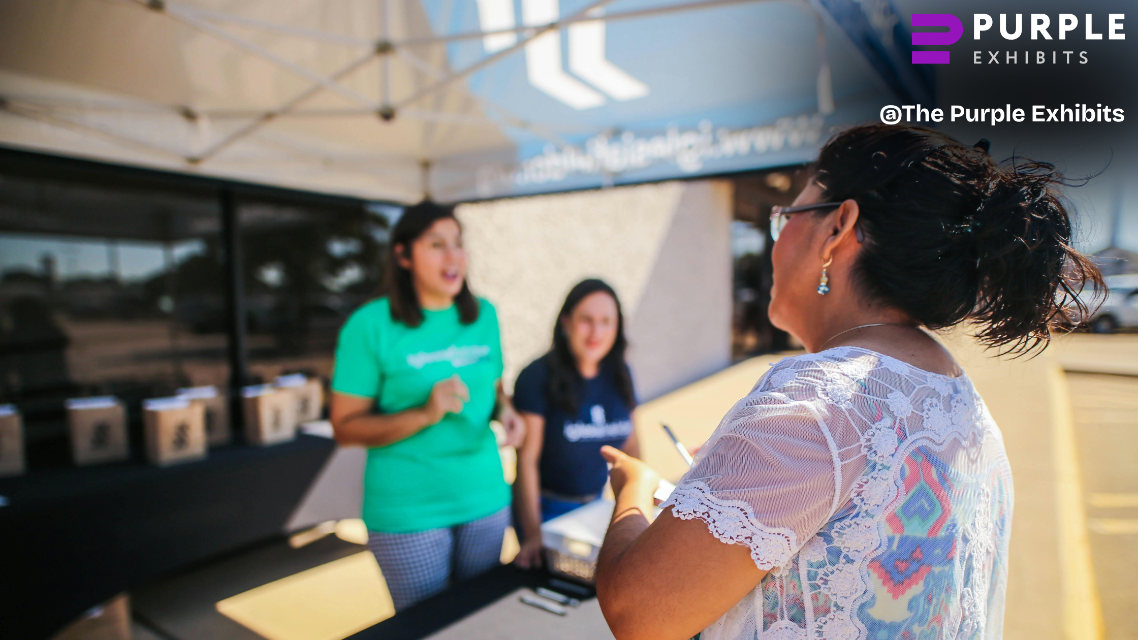 Friendly team members speaking with an attendee outside a setup area, showing how Las Vegas Trade Show Booths benefit from Las Vegas Trade Show Experts.