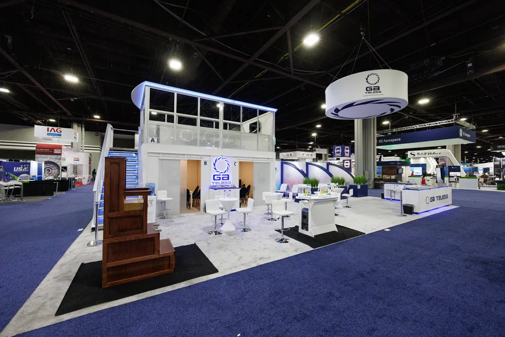 Award-winning 30x50 GA Telesis double-decker exhibit booth with video walls and private meeting spaces at MRO Americas