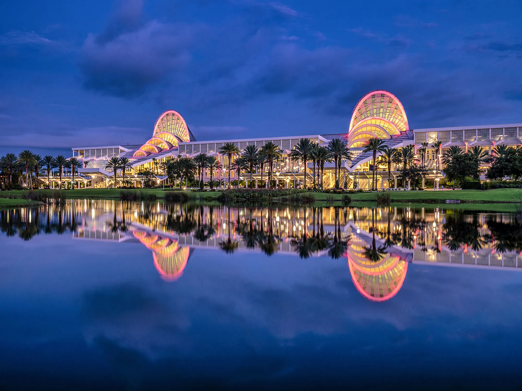 Orange County Convention Center North-South Building at dusk with palm trees and waterfront reflection